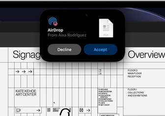 Das Display zeigt die Dynamic Island mit einer AirDrop Anfrage in einem kleinen Fenster über einer geöffneten Adobe Acrobat Datei